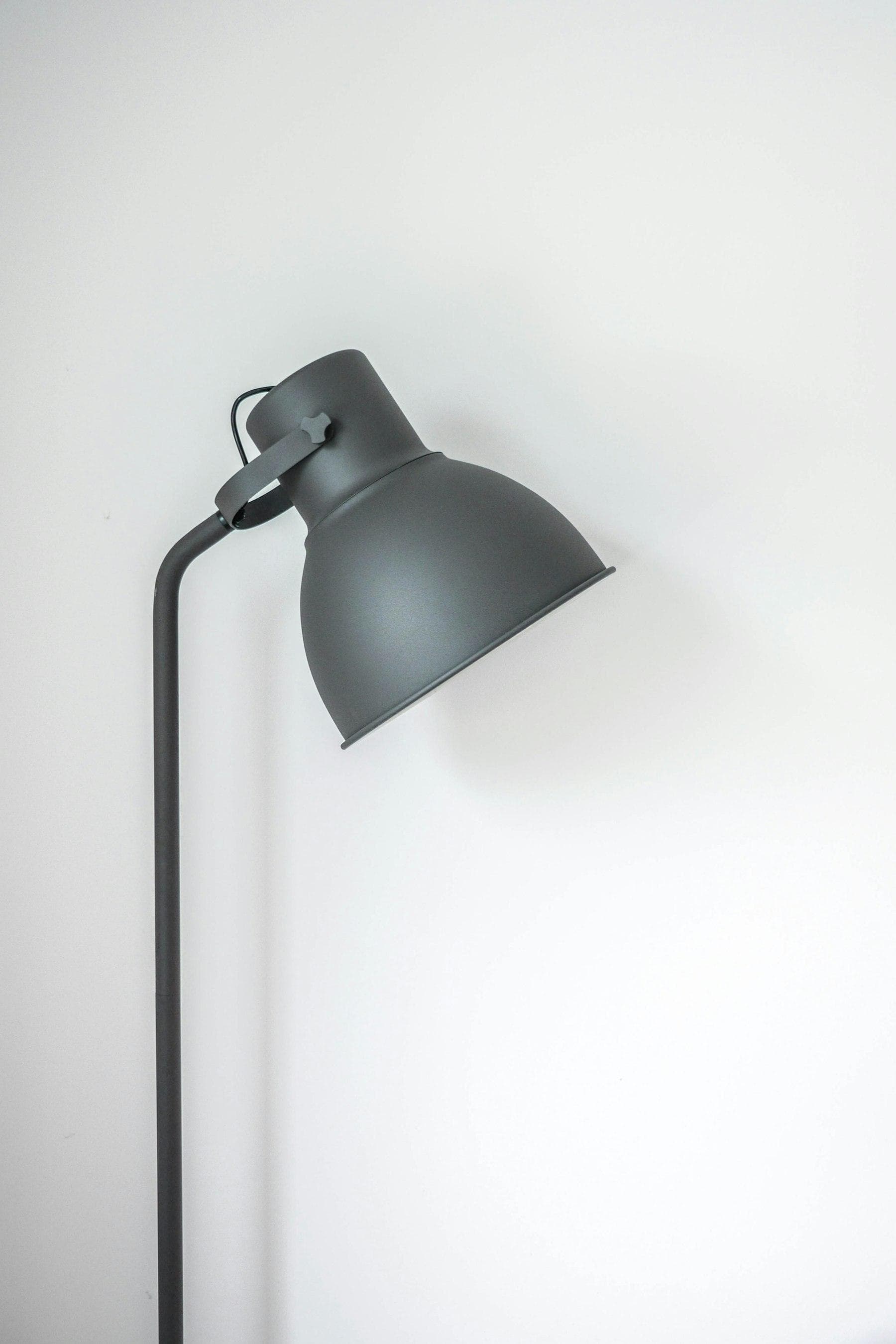 Grey metal floor lamp against a white wall