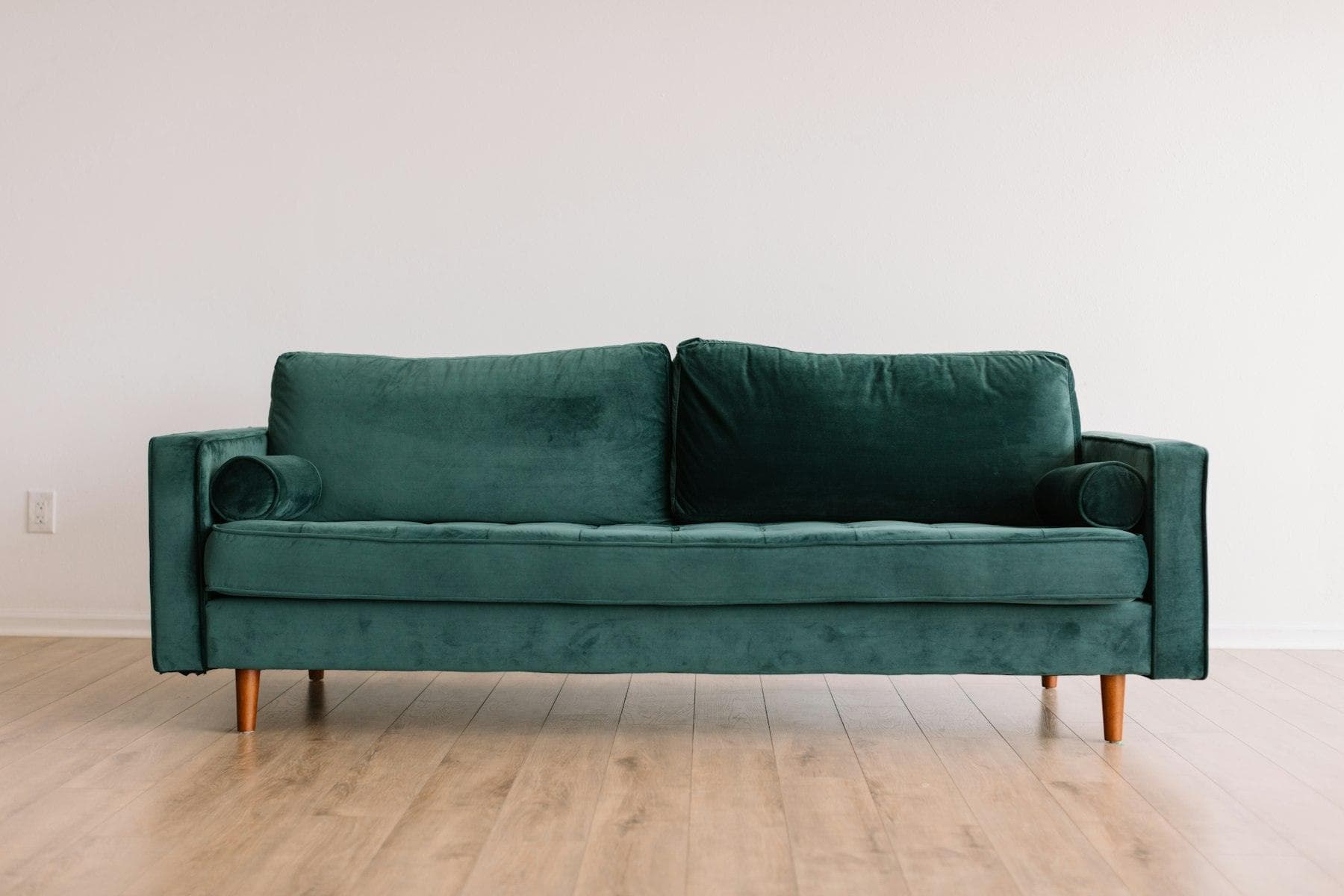Green velvet sofa on a wooden floor